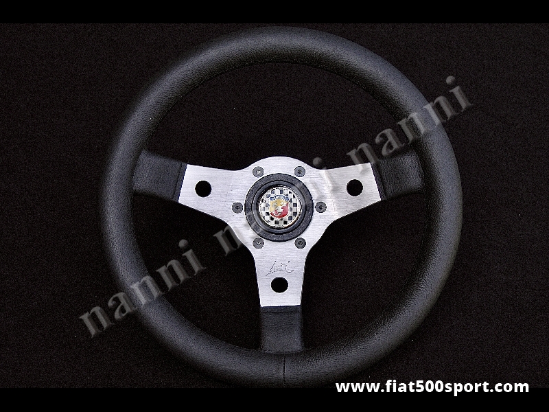 Art. 0010 - Volante Fiat 500 Fiat 126 Abarth in pelle nera a calice con razze satinate completo di mozzo e pulsante clacson Abarth. - Volante Fiat 500 Fiat 126 Abarth in pelle nera a calice con razze satinate, completo di mozzo per Fiat 500 e pulsante clacson Abarth. (Specificare nelle note se lo si desidera con mozzo per 126). Il diametro esterno è di 315 mm. Ha un’ottima impugnatura essendo abbastanza grosso e morbido.
